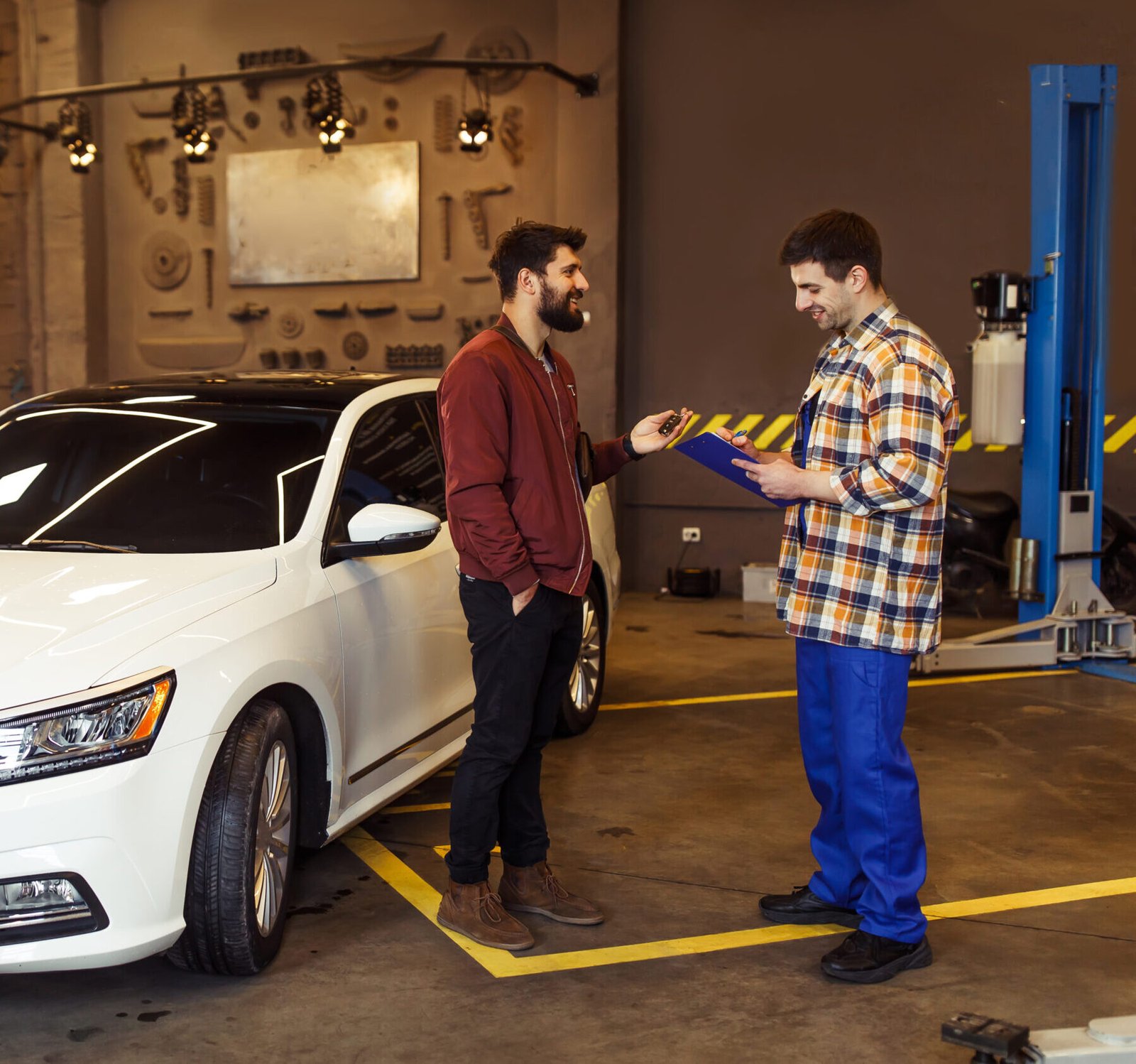 male customer auto service center explaning problems his car mechanic with clipboard scaled e1722531338532